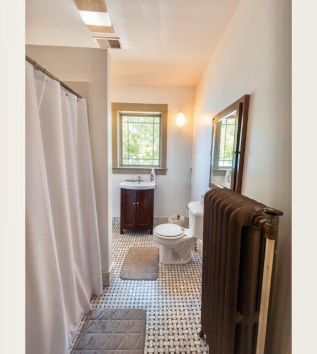 bathroom featuring a shower with shower curtain, vanity, toilet, and radiator