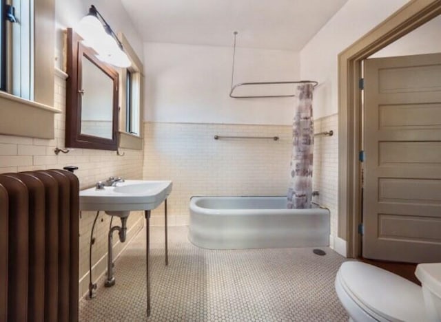 bathroom with radiator, tub / shower combination, tile walls, tile patterned flooring, and toilet