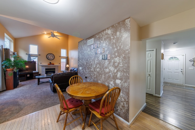 dining area with a tile fireplace, hardwood / wood-style flooring, ceiling fan, and lofted ceiling