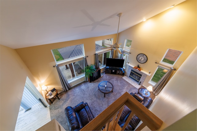 living room featuring carpet flooring, ceiling fan, high vaulted ceiling, and a tiled fireplace