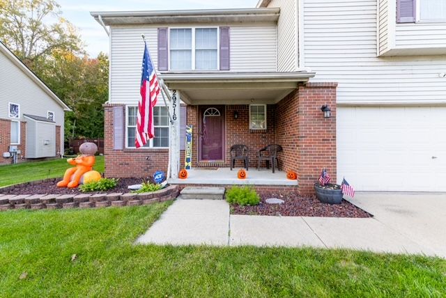 view of front of property featuring covered porch, a garage, and a front lawn