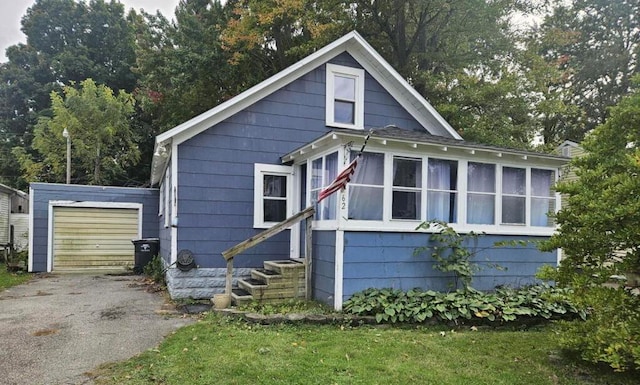 view of home's exterior with a sunroom, a garage, and an outbuilding