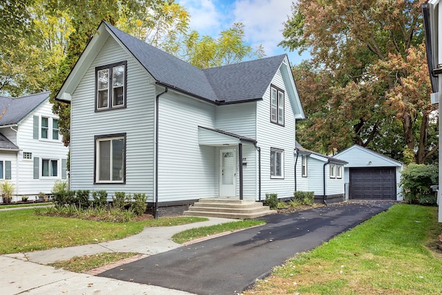 view of property featuring a garage, an outbuilding, and a front lawn