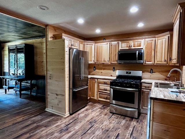 kitchen featuring appliances with stainless steel finishes, light brown cabinetry, sink, dark hardwood / wood-style floors, and butcher block counters