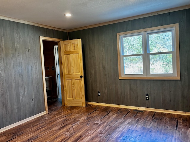 unfurnished room featuring dark wood-type flooring and wood walls