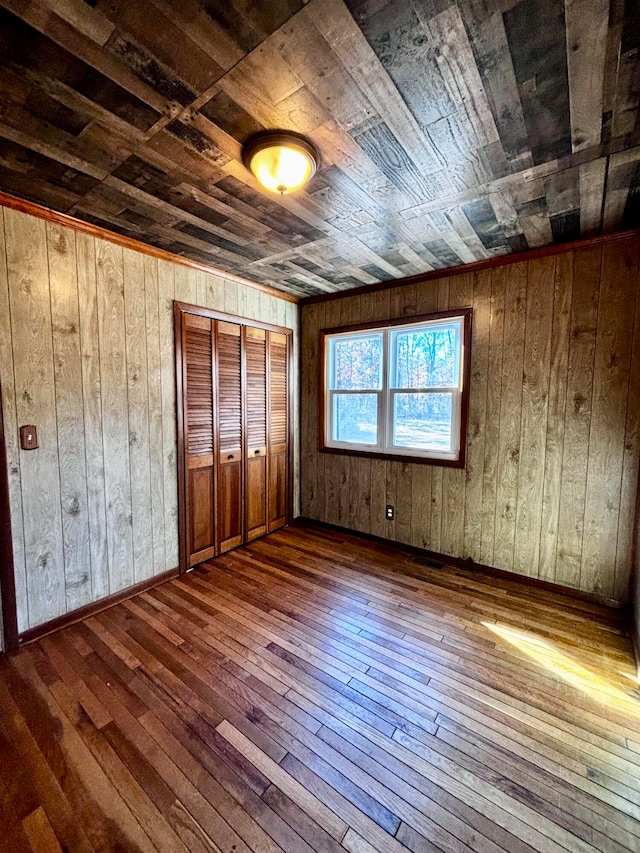 unfurnished bedroom with dark hardwood / wood-style floors, a closet, wooden ceiling, and wood walls