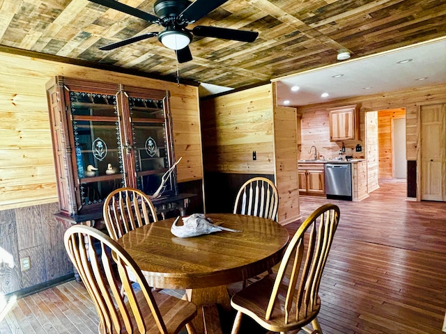 dining area with ceiling fan, sink, wooden walls, wood ceiling, and hardwood / wood-style flooring