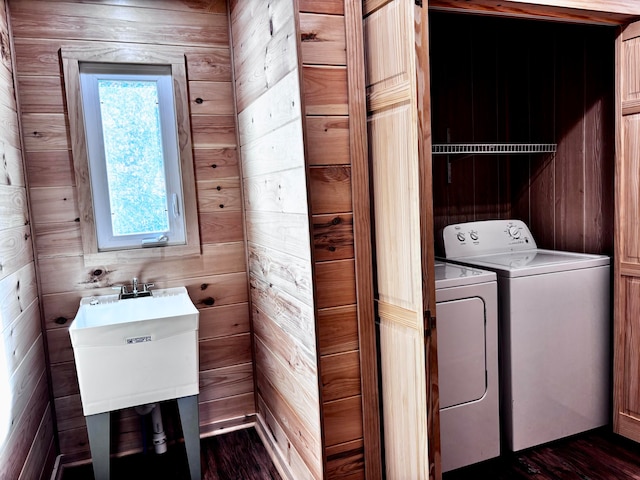 washroom featuring dark hardwood / wood-style floors, wood walls, and washing machine and dryer