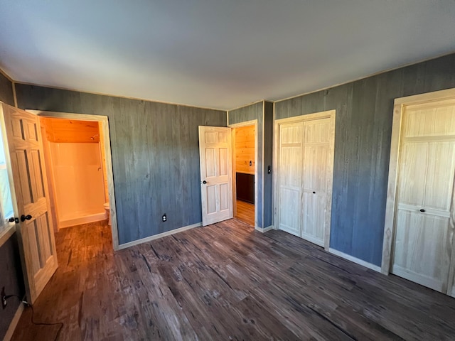 unfurnished bedroom with wood walls and dark wood-type flooring