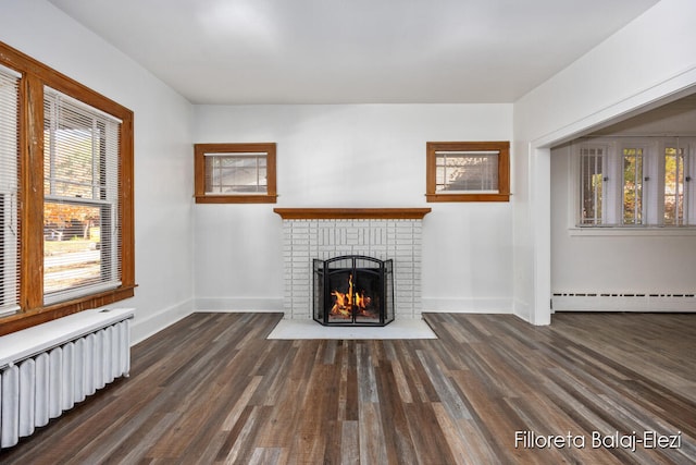 unfurnished living room with a brick fireplace, dark hardwood / wood-style flooring, radiator, and a baseboard heating unit