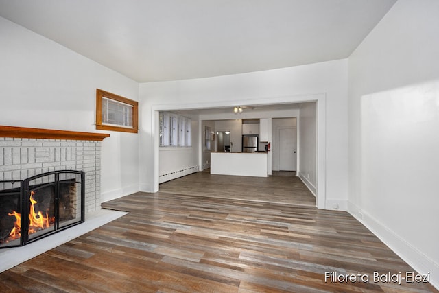 unfurnished living room featuring a fireplace, a baseboard radiator, and hardwood / wood-style flooring