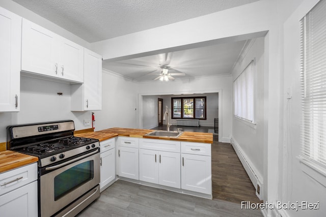 kitchen with wood counters, stainless steel range with gas cooktop, sink, light hardwood / wood-style flooring, and white cabinetry