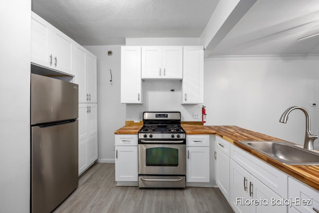 kitchen featuring butcher block countertops, white cabinets, sink, and appliances with stainless steel finishes