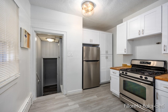 kitchen with butcher block countertops, white cabinetry, and stainless steel appliances