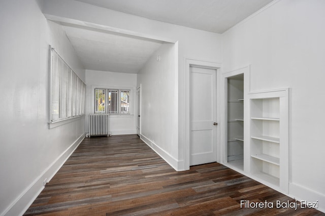 corridor featuring radiator, built in shelves, and dark wood-type flooring