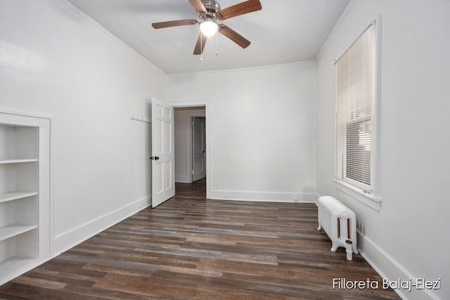 unfurnished room featuring built in shelves, ceiling fan, radiator heating unit, dark hardwood / wood-style floors, and ornamental molding