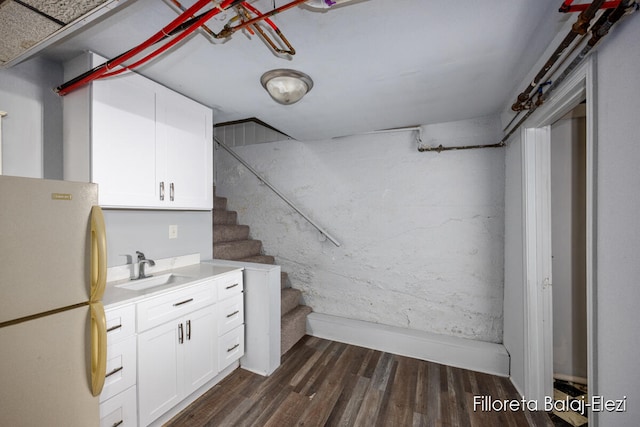 basement featuring sink, dark hardwood / wood-style floors, and white refrigerator