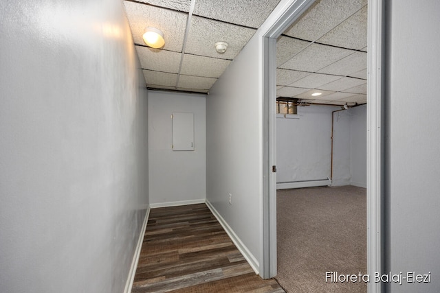 corridor featuring a drop ceiling, dark hardwood / wood-style floors, and a baseboard heating unit