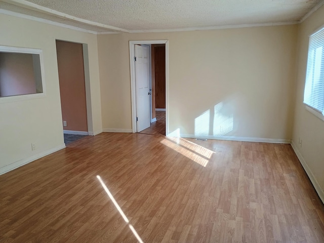 spare room featuring light hardwood / wood-style floors and a textured ceiling