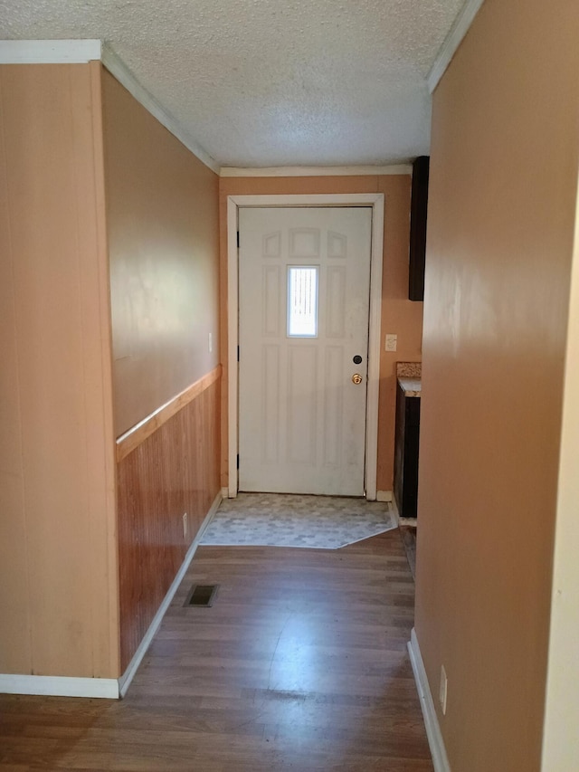 doorway featuring hardwood / wood-style flooring, crown molding, and a textured ceiling