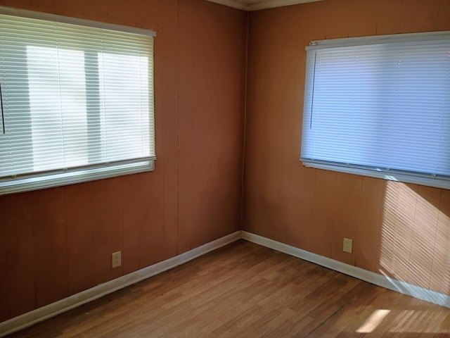 empty room featuring wood-type flooring and wooden walls