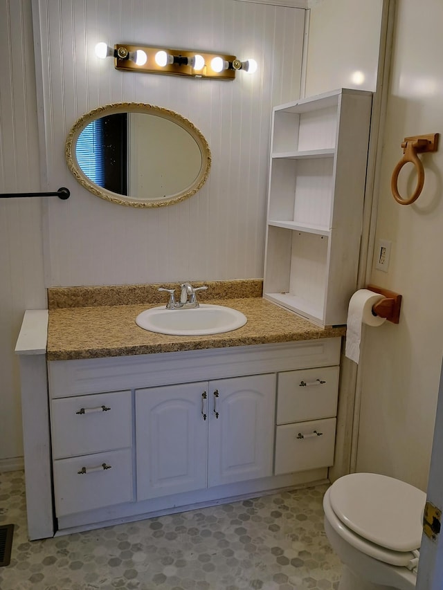 bathroom with vanity, toilet, and wood walls