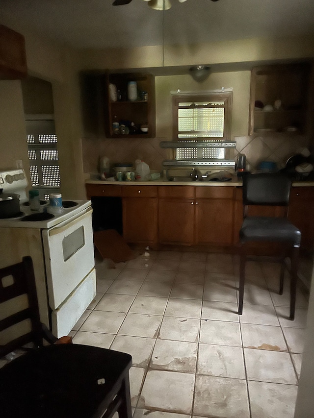 kitchen featuring ceiling fan, sink, white range with electric stovetop, backsplash, and light tile patterned flooring