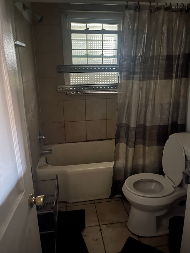 bathroom with tile patterned floors, shower / bath combination with curtain, and toilet