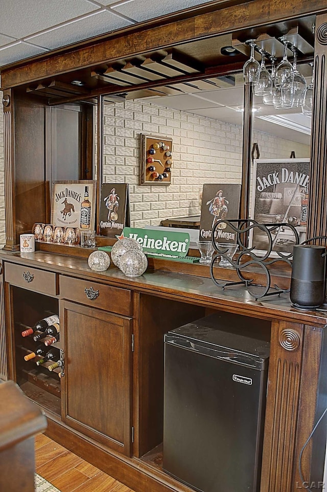 bar with brick wall, stainless steel fridge, and light wood-type flooring