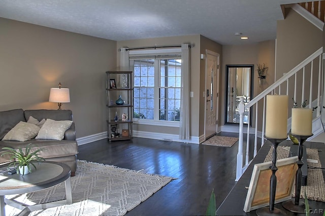 living room with a textured ceiling and dark hardwood / wood-style flooring