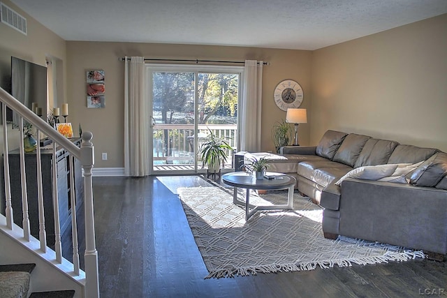 living room featuring dark wood-type flooring and a textured ceiling