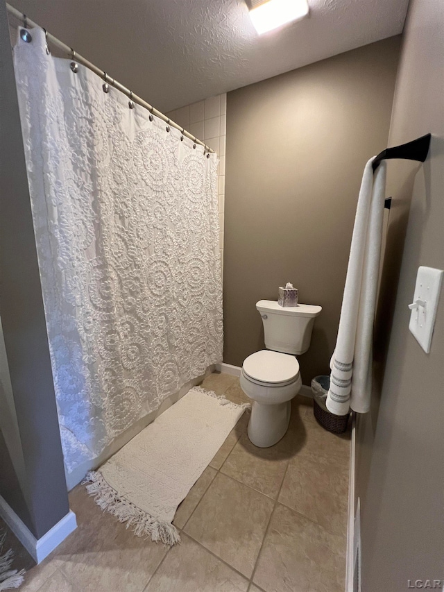 bathroom with a textured ceiling, tile patterned floors, and toilet