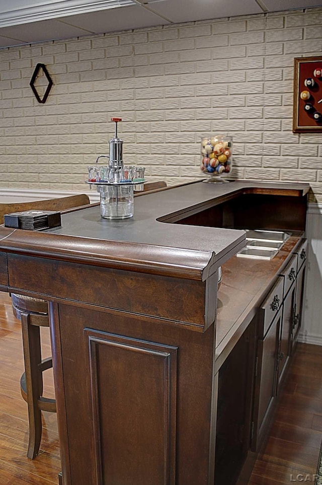 bar with dark brown cabinetry, hanging light fixtures, and dark wood-type flooring