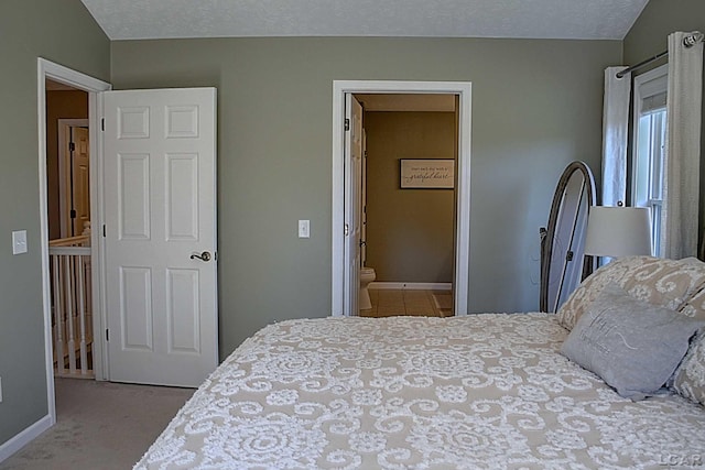 bedroom featuring carpet floors, a textured ceiling, and ensuite bath