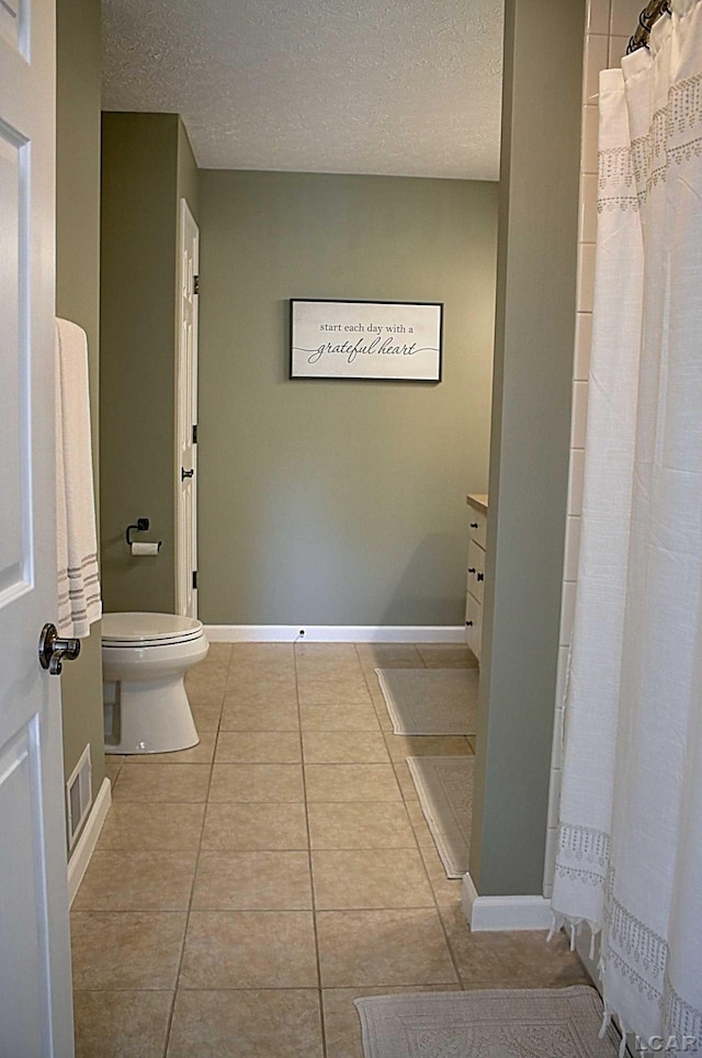 bathroom with tile patterned floors, toilet, vanity, and a textured ceiling