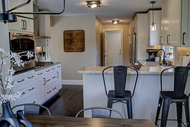 kitchen featuring sink, light stone countertops, hanging light fixtures, and white cabinets