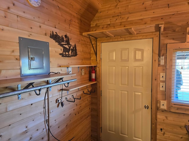 interior space featuring wooden walls, electric panel, and vaulted ceiling