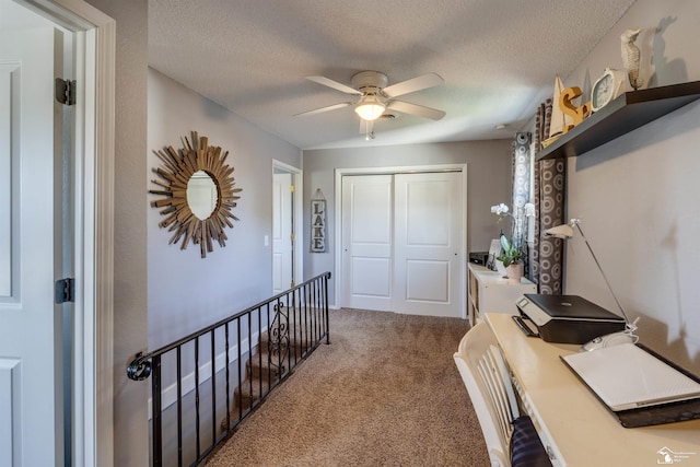 office area with a ceiling fan, carpet flooring, and a textured ceiling