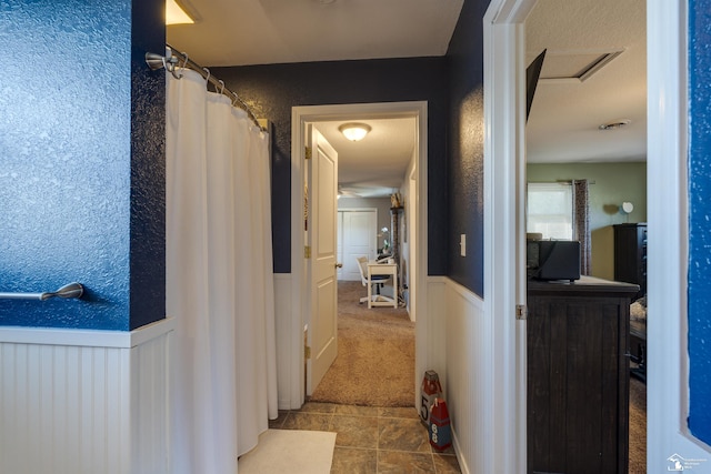 hall featuring tile patterned floors, carpet floors, and wainscoting