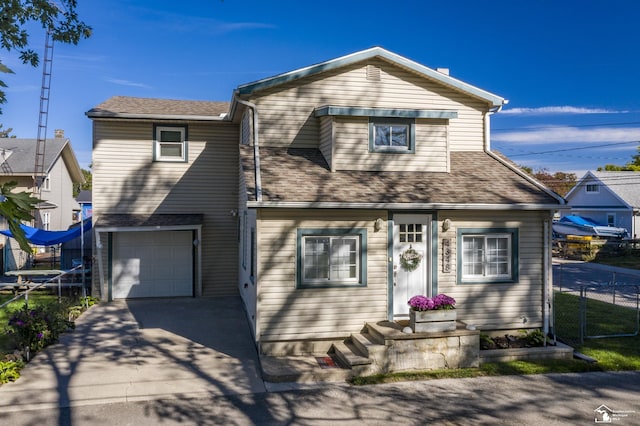 traditional home with fence, driveway, a shingled roof, and an attached garage