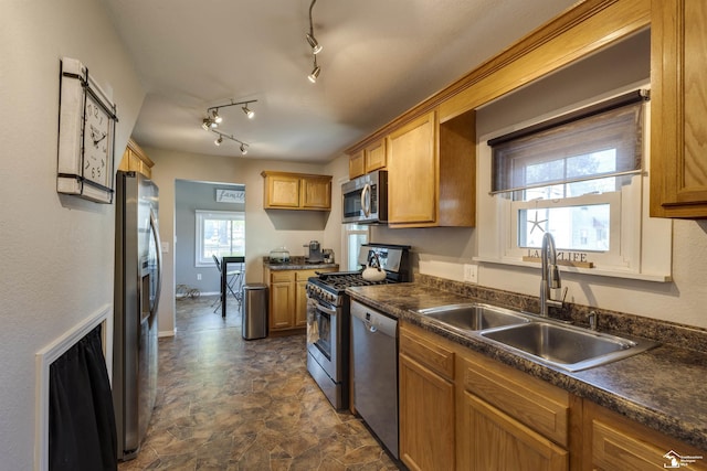 kitchen featuring brown cabinetry, dark countertops, appliances with stainless steel finishes, and a sink