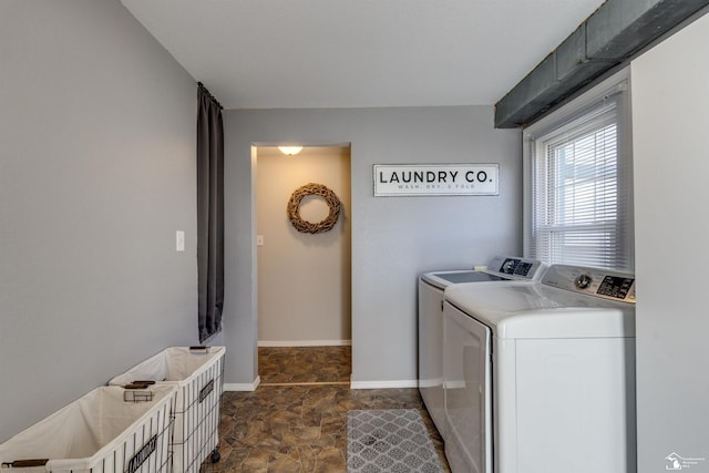 laundry room featuring baseboards, stone finish flooring, laundry area, and washing machine and dryer