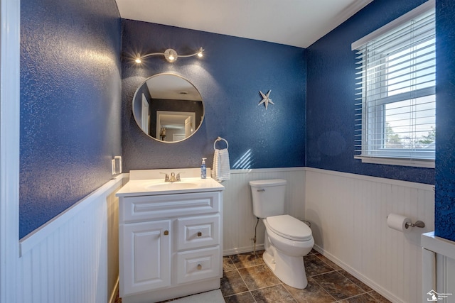 bathroom featuring toilet, tile patterned floors, wainscoting, and vanity