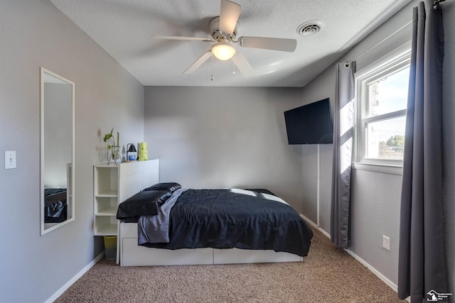 carpeted bedroom featuring ceiling fan and a textured ceiling