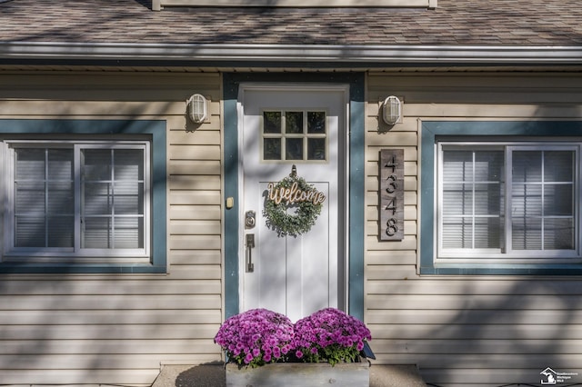 doorway to property with a shingled roof