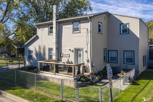 back of house featuring a fenced front yard, a yard, a gate, a chimney, and a deck