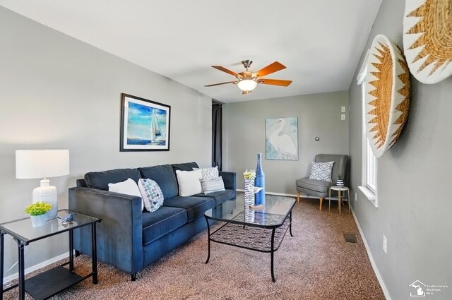 living area featuring visible vents, a ceiling fan, carpet flooring, and baseboards