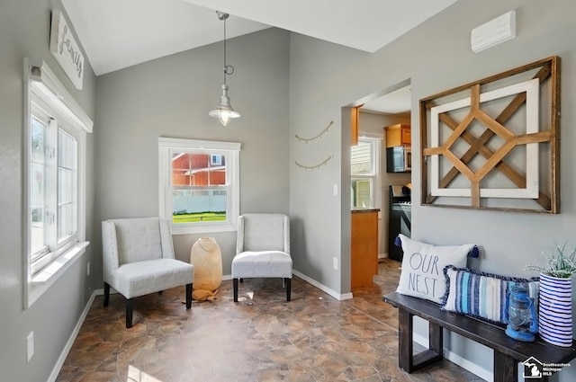 living area with stone finish floor, vaulted ceiling, and baseboards