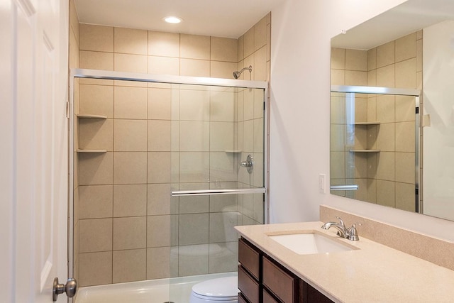 bathroom with vanity, toilet, and a shower with shower door