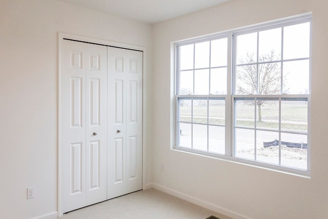 unfurnished bedroom with carpet flooring, a closet, and multiple windows